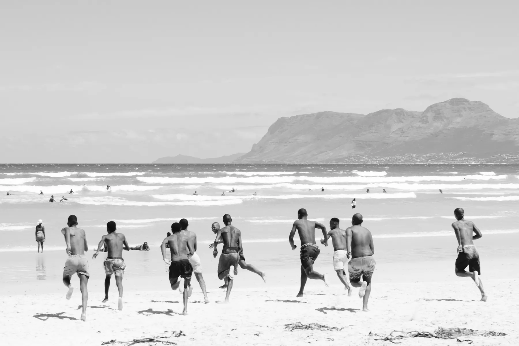 A group of young people running into the sea on a beach near Cape Town